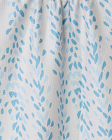 Close-up of the GEOMETRY Reeds Printed - Midday tea towel, showcasing white fabric decorated with scattered light and medium blue leaf-inspired shapes and a gathered top.