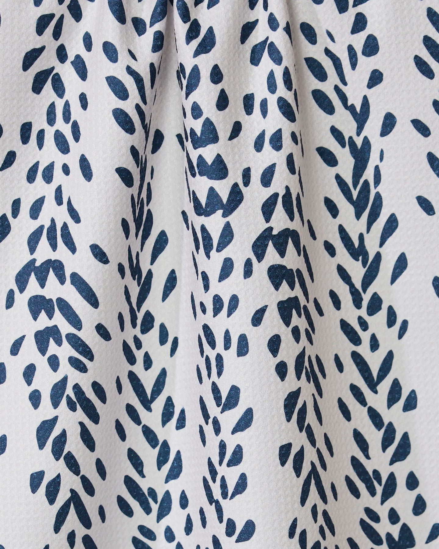 The Reeds Printed - Midnight tea towel by GEOMETRY features ultra-absorbent white fabric with a geometric, navy leaf-like pattern and elegant texture—perfect as a stylish addition to any kitchen.