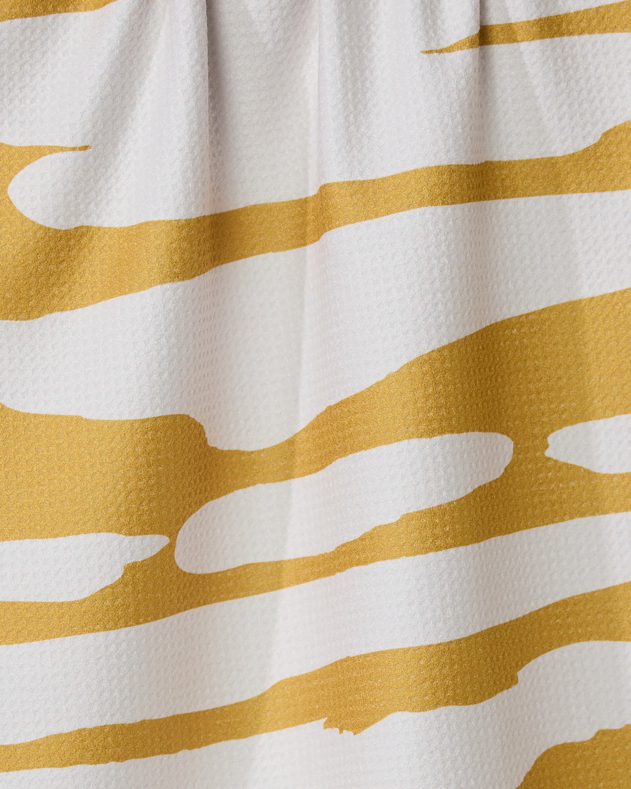 Close-up of the GEOMETRY Reflected - Midday kitchen tea towel, showcasing an abstract yellow and white, wavy striped design. Made from ultra-absorbent, textured fabric with subtle folds—ideal for everyday use.