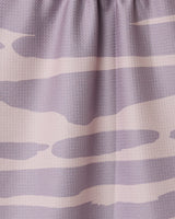 Close-up of the GEOMETRY Reflected - Sunset tea towel, made from recycled materials and featuring a light purple and beige abstract wavy pattern. The fabric is slightly gathered at the top.