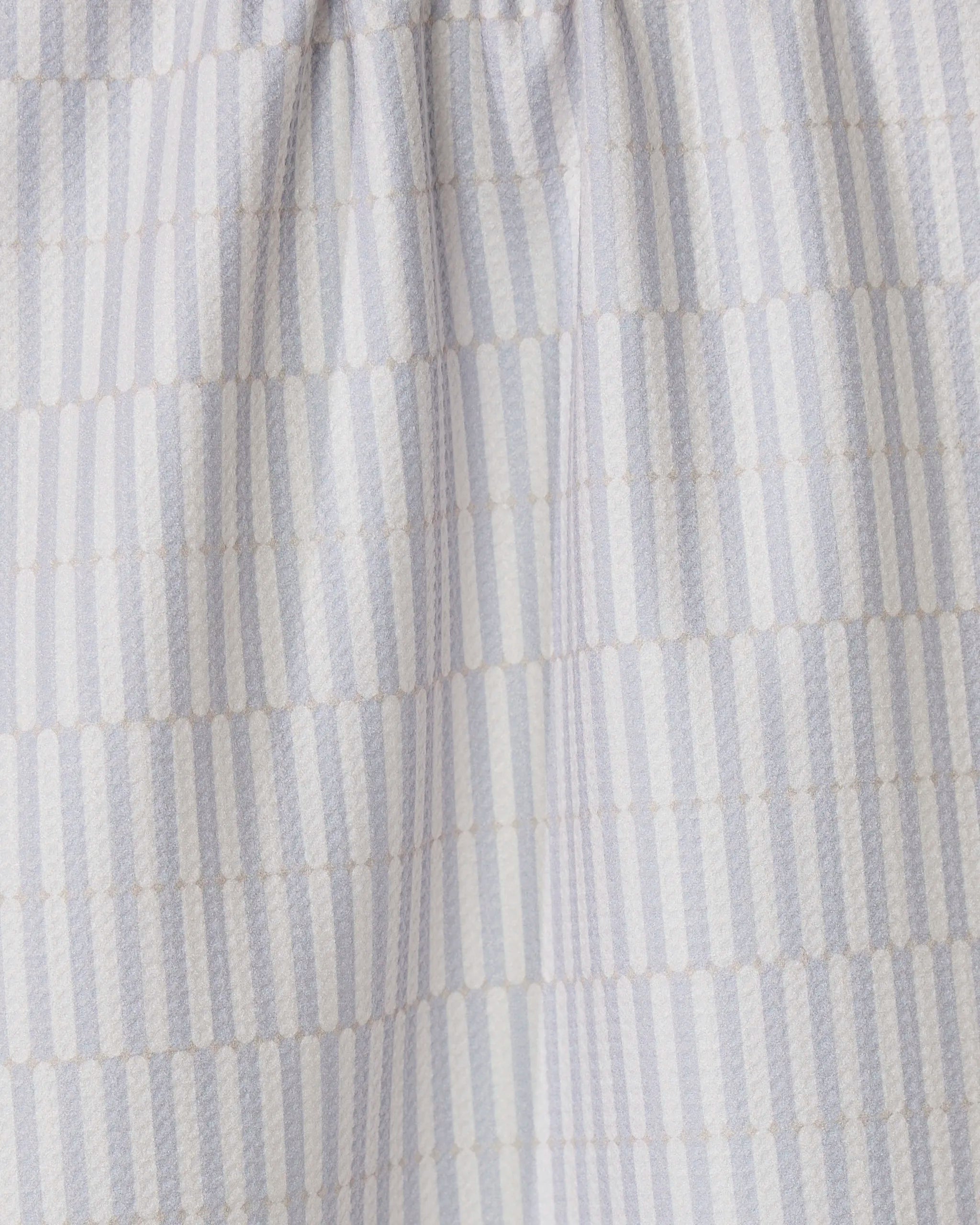 The Rideaux Neutre tea towel by GEOMETRY features white fabric with vertical stripes of small beige dots in a subtle geometric pattern. Slightly gathered at the top, its an eco-friendly and stylish choice for any kitchen.