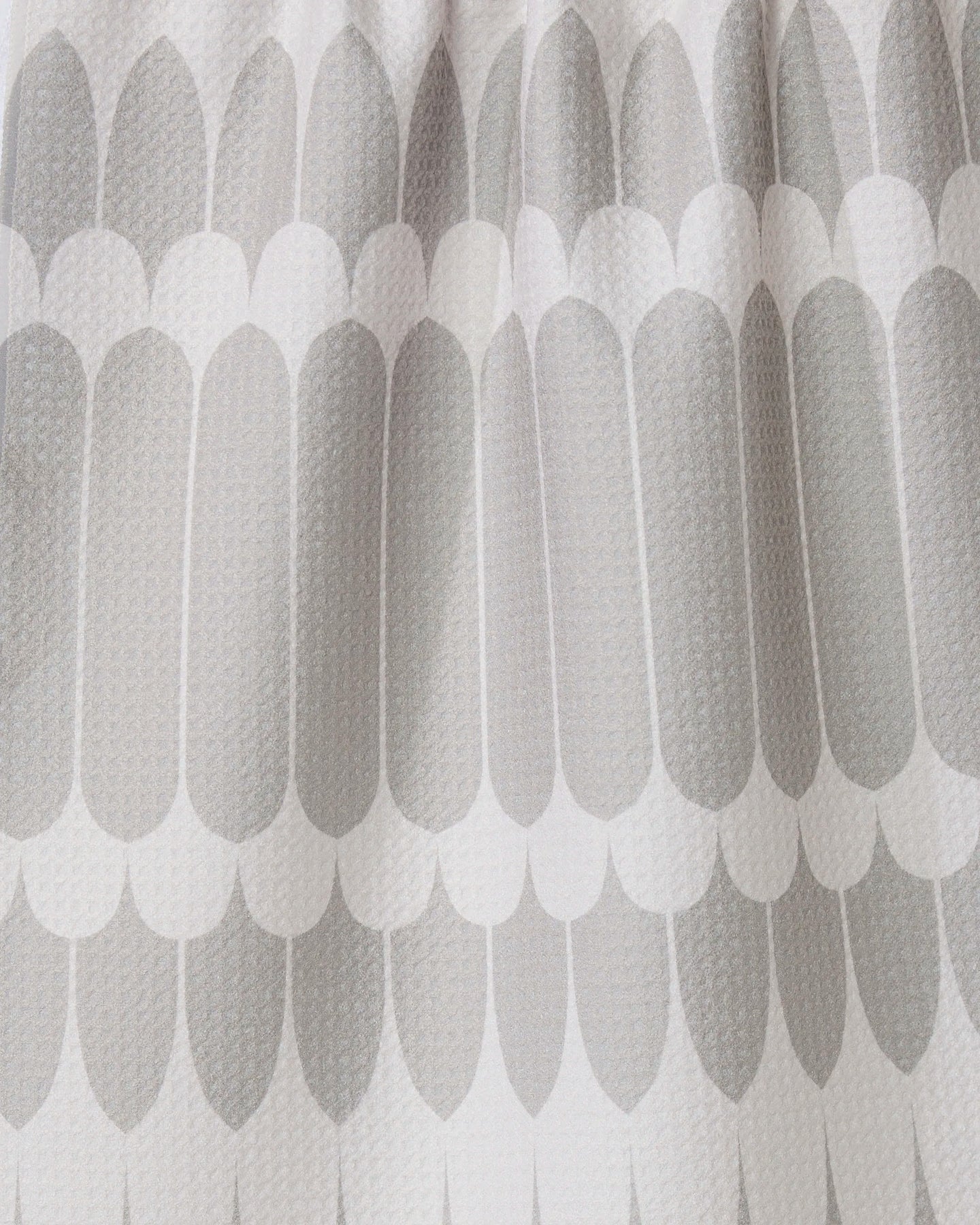 Close-up of the GEOMETRY Salle Dor white kitchen tea towel, showcasing a textured fabric with a repeating pattern of elongated, rounded grey shapes in overlapping rows for a modern look.