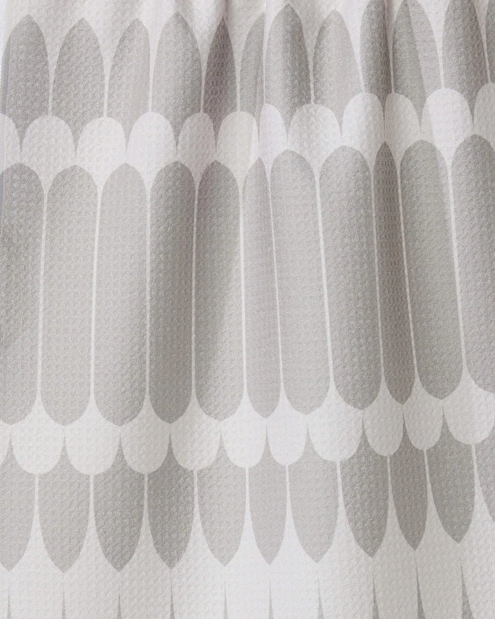 Close-up of the GEOMETRY Salle Dor white kitchen tea towel, showcasing a textured fabric with a repeating pattern of elongated, rounded grey shapes in overlapping rows for a modern look.