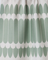 Close-up of GEOMETRY’s Salle Verte tea towel, showing its repeating green oval geometric pattern and white scalloped edges. The ultra-absorbent, textured towel features a modern symmetrical design with visible folds for added depth.