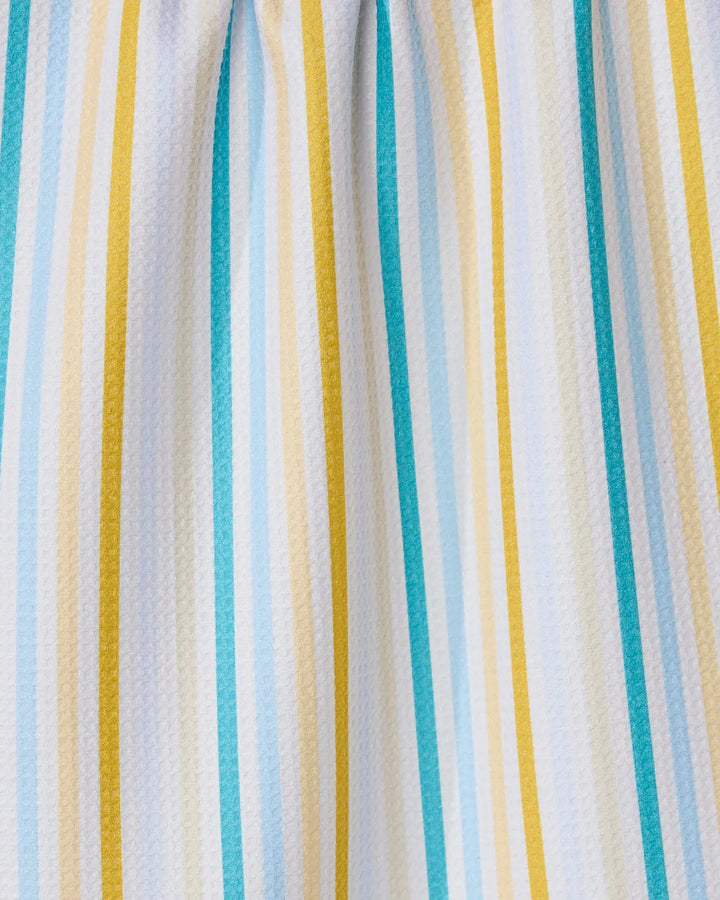 A close-up of GEOMETRYs Seaside Sunshine recycled kitchen towel, featuring vertical stripes in yellow, teal, light blue, and white. Its fabric is slightly gathered at the top for soft folds and a textured look.
