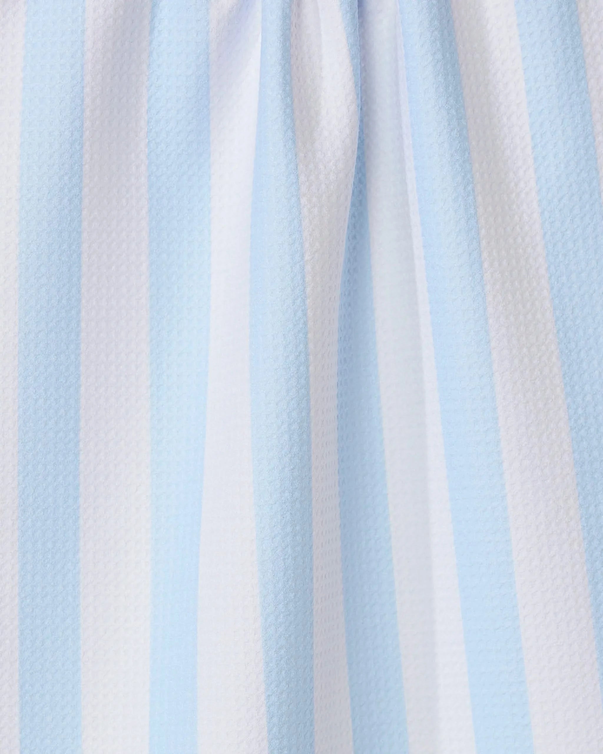 Close-up of the GEOMETRY Seaside Stripes recycled kitchen towel, showcasing its light blue and white vertical stripes, textured surface, and gentle folds.