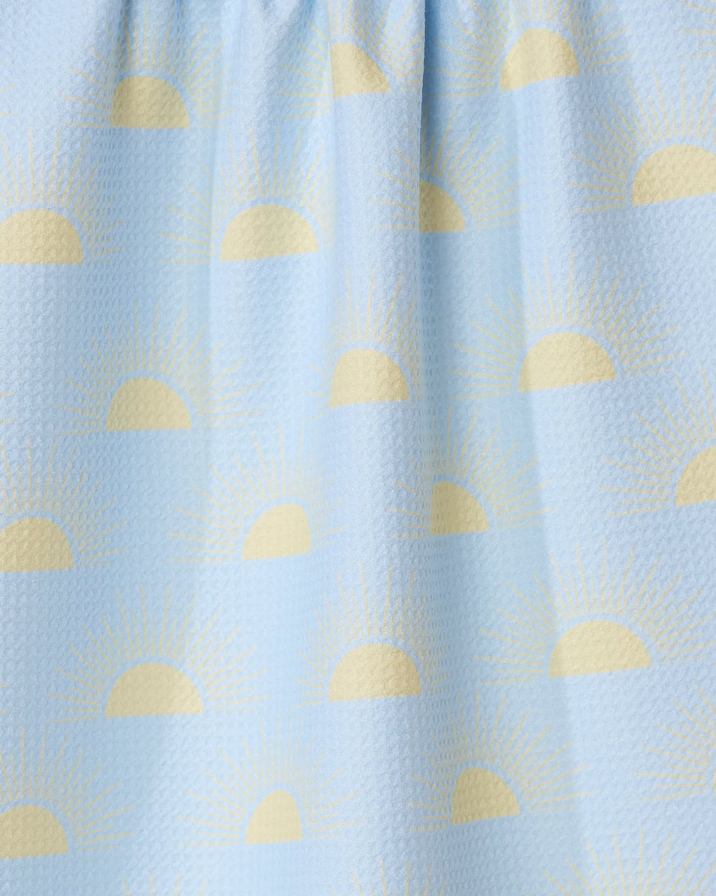The GEOMETRY Soft Summer Sun tea towel features a light blue textured design with yellow half sun and sunbeam patterns, made from recycled materials.