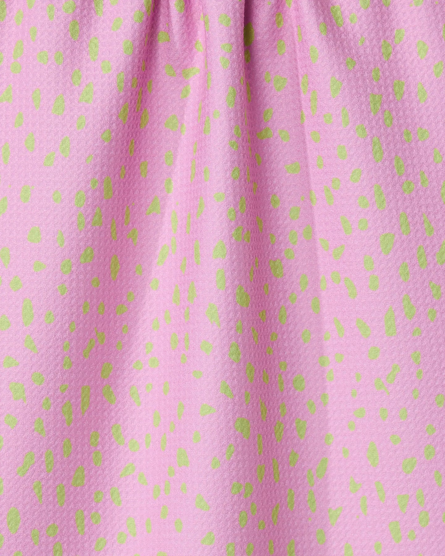 Close-up of GEOMETRYs Speckle Pink tea towel, made from recycled materials and featuring a pink textured design with small green dots and gathered folds at the top.