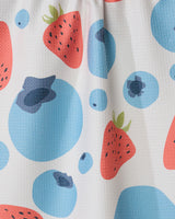 A close-up of the GEOMETRY Sunny Berries recycled kitchen towel, showcasing a colorful pattern with red strawberries and blue blueberries on a white background.
