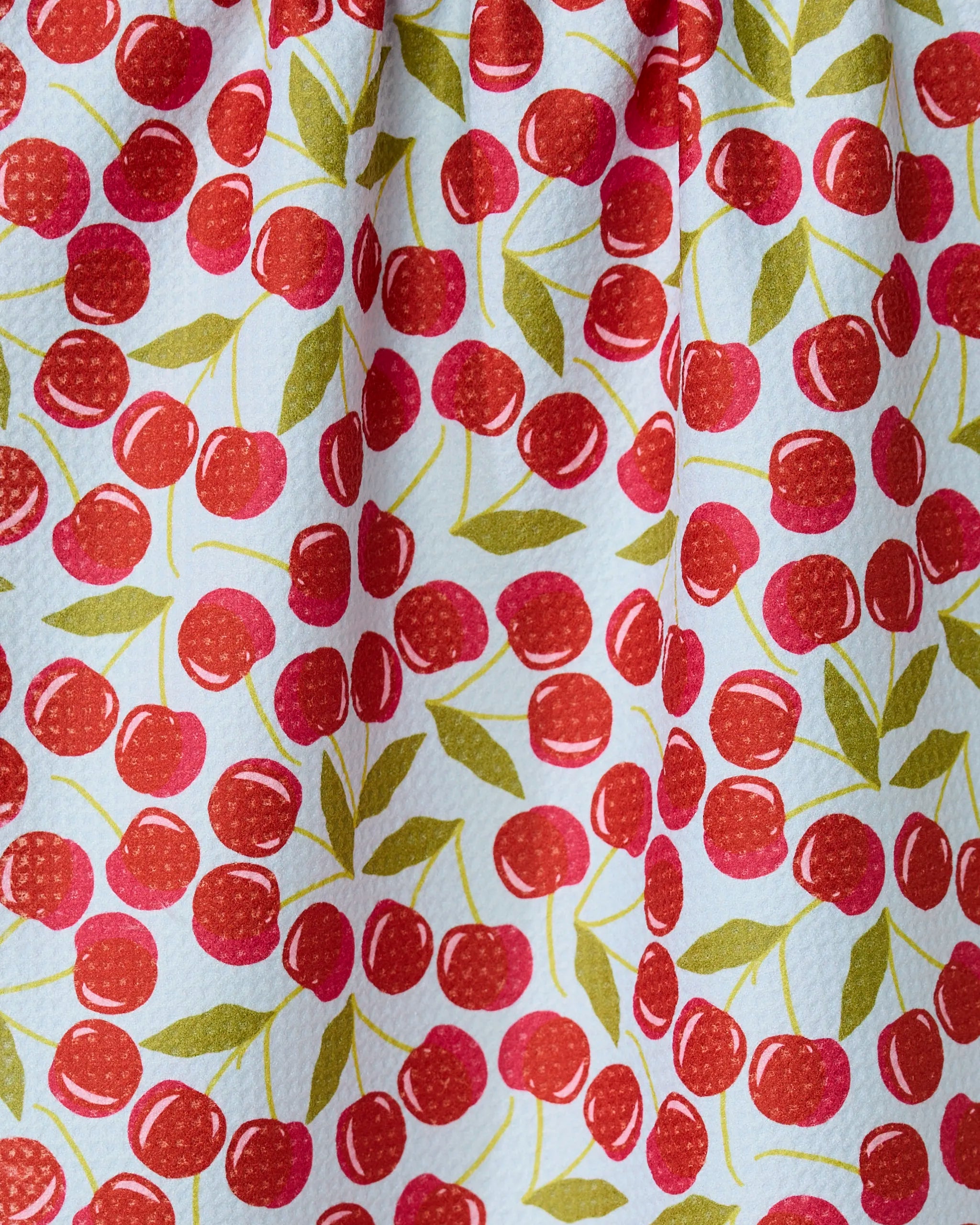 The GEOMETRY Sweet Cherry towel features a colorful cherry pattern with red cherries and green leaves on white. Quick-drying and slightly textured, it’s gathered at the top, perfect for adding a cheerful touch to your kitchen.