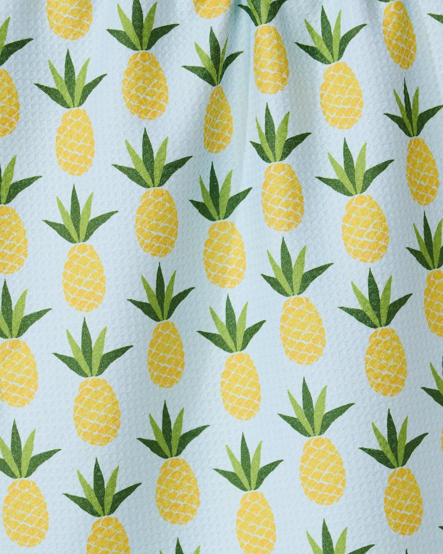 The GEOMETRY Sweet Pineapple tea towel features a repeating pattern of yellow pineapples with green leaves on a light blue textured background, adding a cheerful touch to your kitchen décor.
