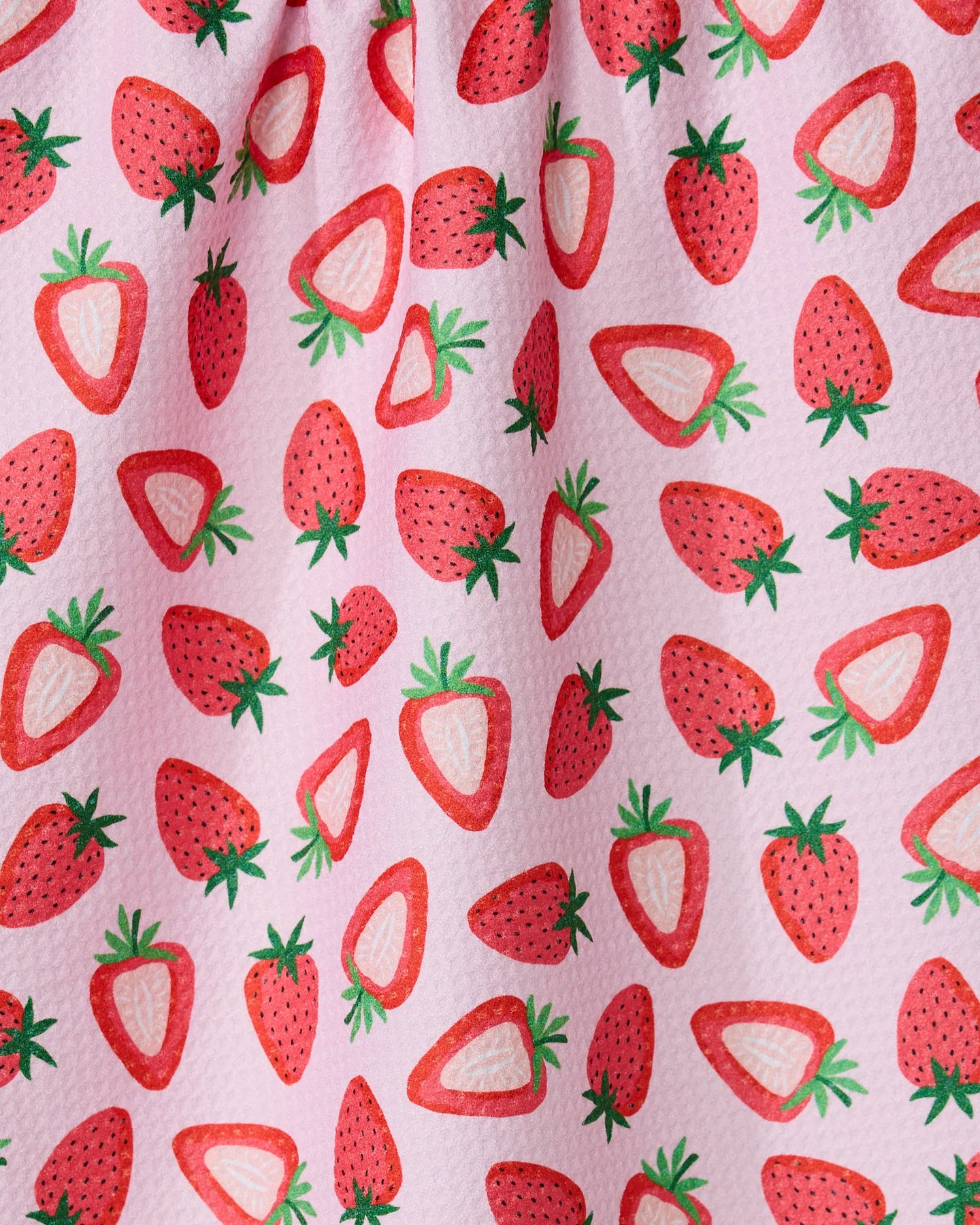 The Sweet Strawberry tea towel by GEOMETRY features a playful pink fabric with whole and sliced red strawberries, green leaves, and is crafted from recycled materials.