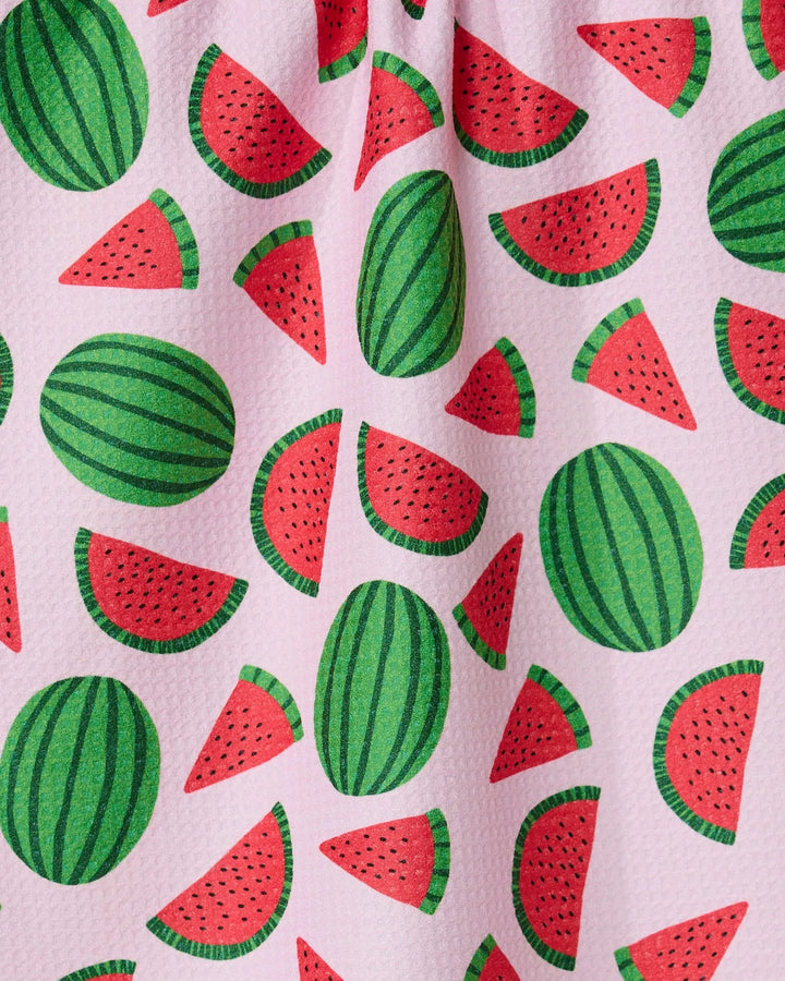 The GEOMETRY Sweet Watermelon kitchen tea towel has a pink textured surface with a playful green and red watermelon and slice pattern scattered across it.