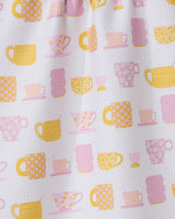 The GEOMETRY Talk Over Tea towel features a white textured design with yellow and pink cup-and-saucer patterns—adorned with flowers, grids, and dots—and is crafted from recycled materials for stylish sustainability in your kitchen.