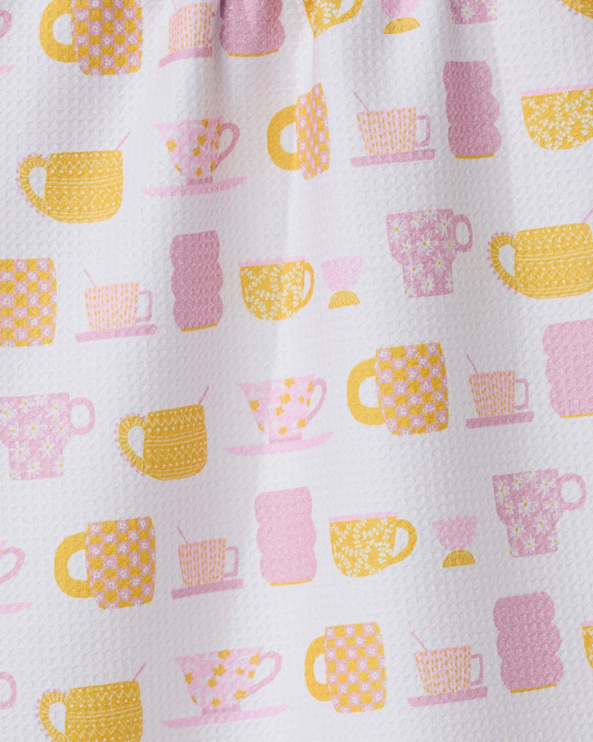 The GEOMETRY Talk Over Tea towel features a white textured design with yellow and pink cup-and-saucer patterns—adorned with flowers, grids, and dots—and is crafted from recycled materials for stylish sustainability in your kitchen.