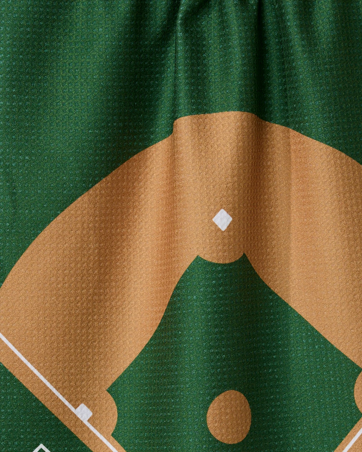 A close-up of The Field by GEOMETRY—a quick-drying tea towel made from recycled materials—shows a baseball field diagram on green and brown textured fabric, featuring the infield and part of the outfield.