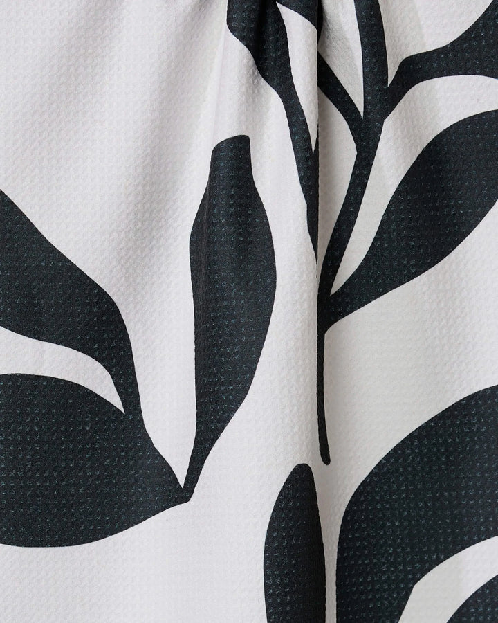 Close-up of the Threes tea towel by GEOMETRY, ultra-absorbent and made from recycled materials, featuring a bold black and white abstract leaf pattern on a textured light background.