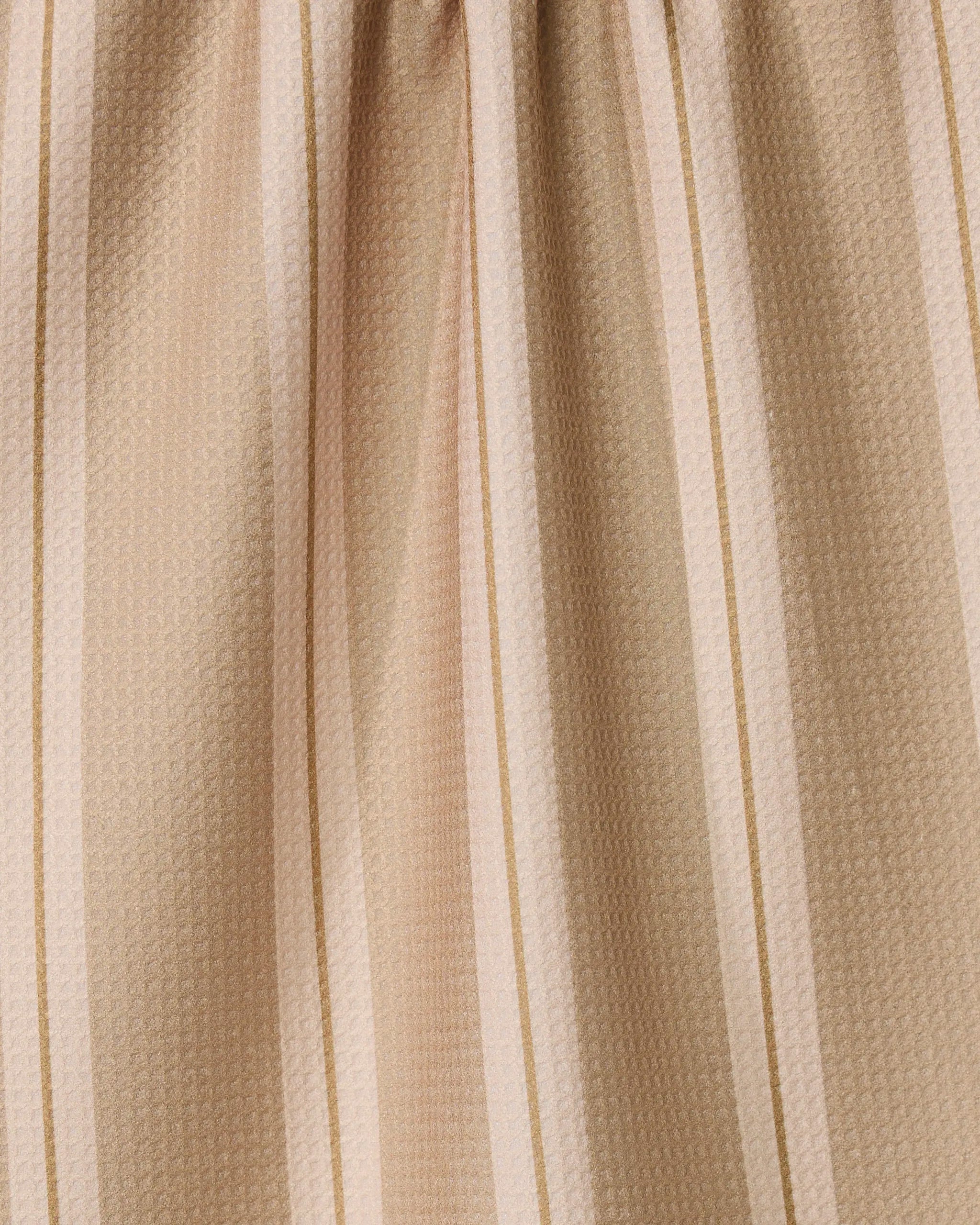 The GEOMETRY Vanilla Chai kitchen towel, made from recycled materials, features beige fabric with light and dark tan stripes, a subtle textured pattern, gentle gathers, and ultra-absorbent performance.