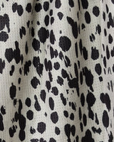 Close-up of Geometrys Cass recycled kitchen towel, showing a black and white Dalmatian-style spotted pattern with a lightly textured, woven surface and irregular black spots on a pale background.