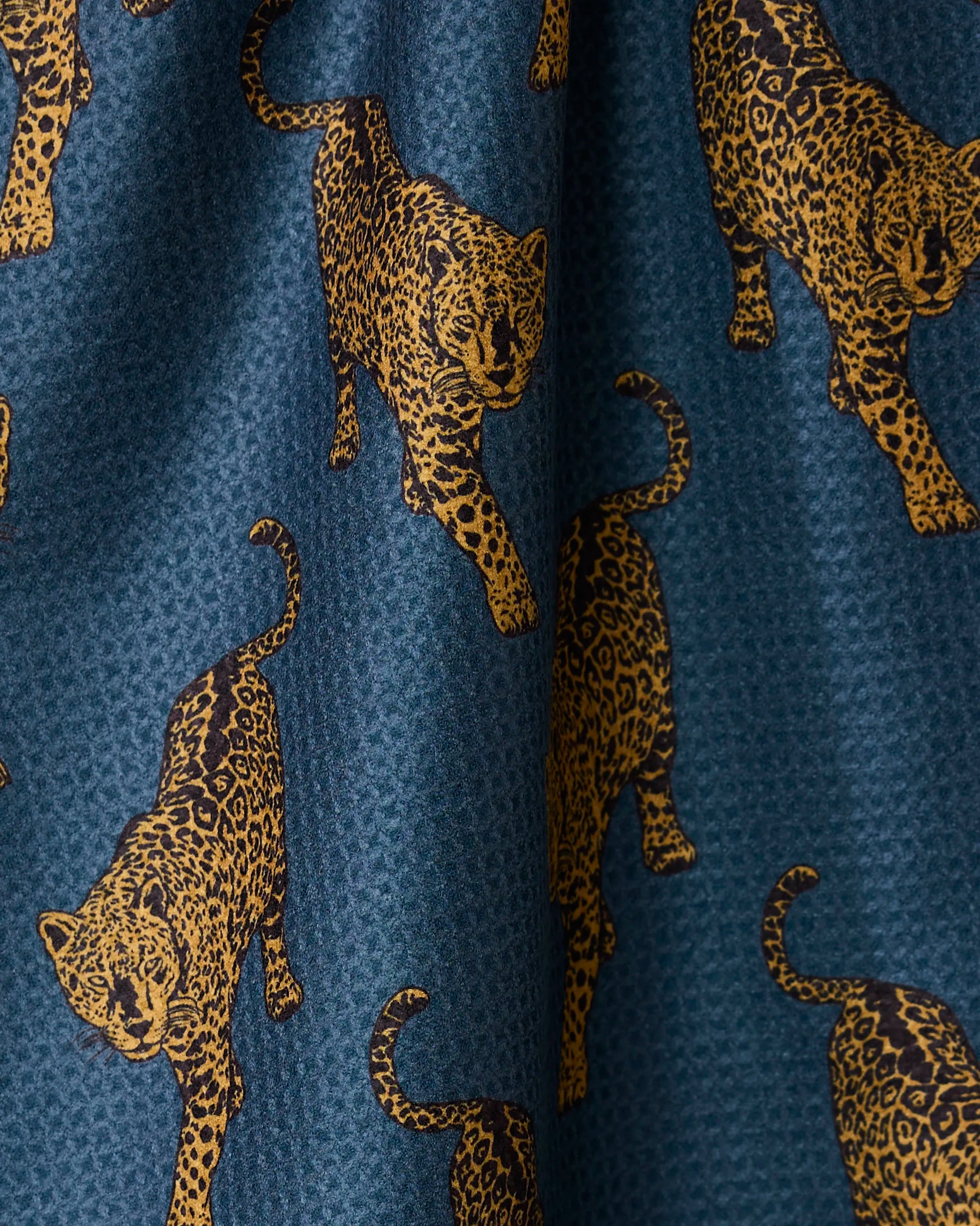 Leopard Lovin by Geometry is a quick-drying blue tea towel featuring golden-yellow leopards in walking poses—a stylish, practical addition to any kitchen.