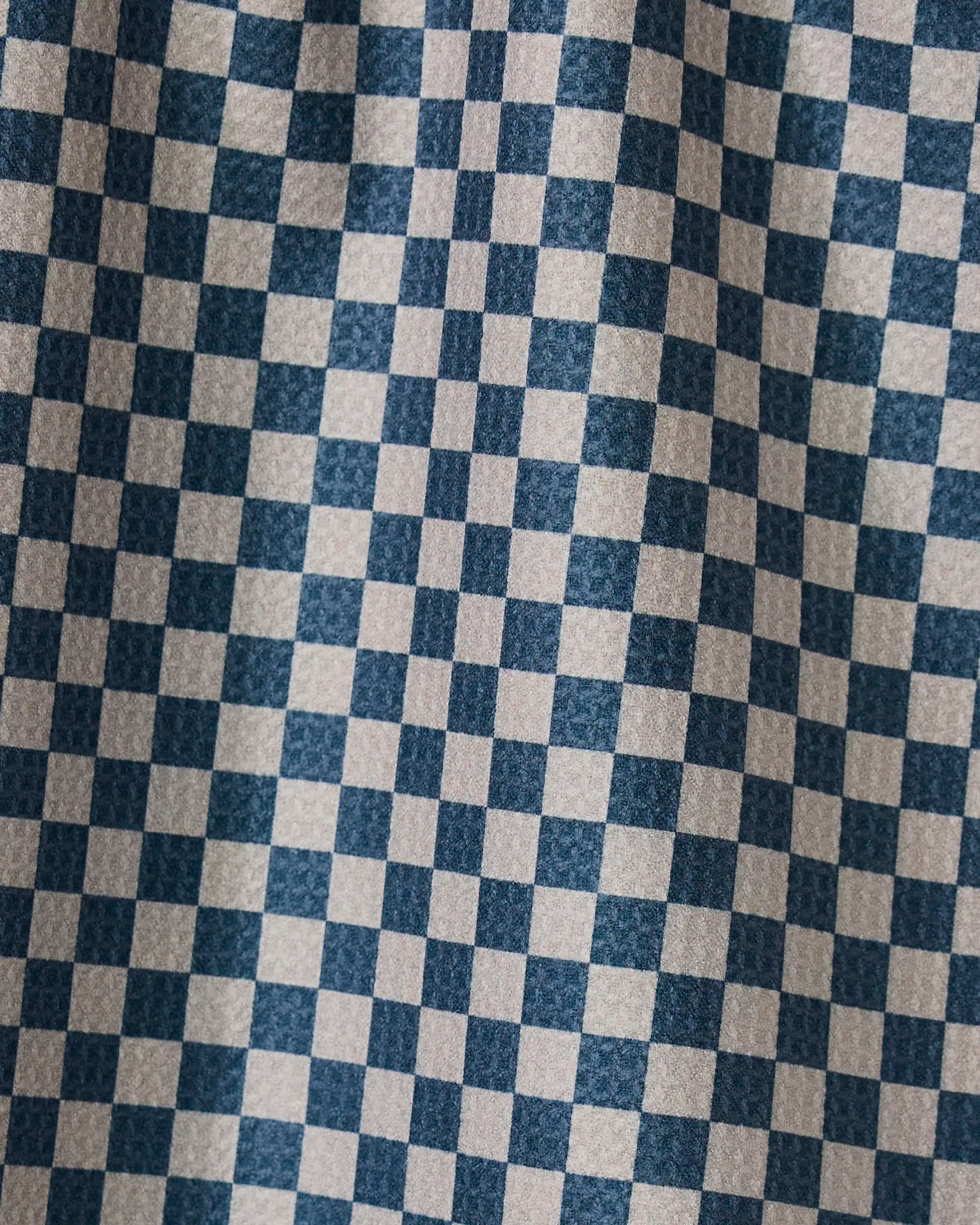 A close-up of the Leopard Lovin tea towel by Geometry shows its stylish blue and white checks, with soft folds and shadows accentuating the practical double-sided design.