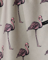 The Geometry Flamingo Dance tea towel features gray textured fabric with illustrated pink flamingos in various poses and a small black tag on the right side.