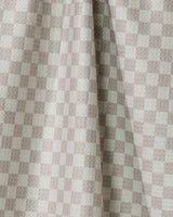 Flamingo Dance by Geometry features light beige and cream checkered drapes made from recycled kitchen towels, with a visible center fold that casts soft shadows and highlights the textured look of the small, even squares.