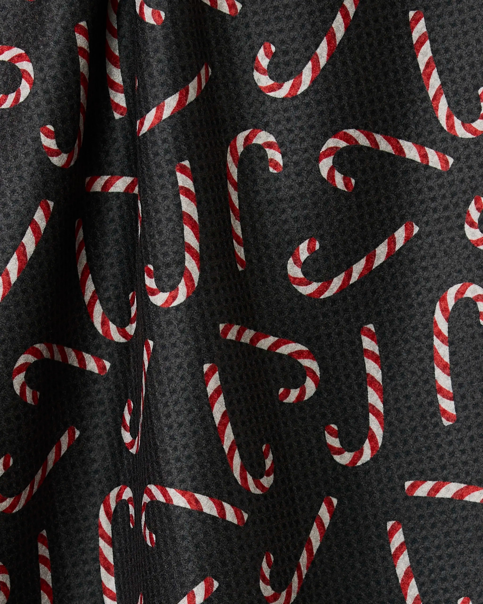 Geometry’s Sweet Canes tea towel features a black double-sided fabric with red and white striped candy canes in every direction, adding festive style and function to your kitchen.