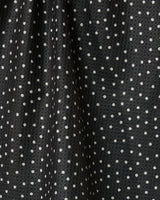 Close-up of the Geometry Sweet Canes tea towel, featuring quick-drying black fabric with evenly spaced white polka dots, soft folds, and a slight sheen that creates subtle texture and shadows.