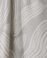 Close-up of Geometrys Stone tea towel in light gray textured fabric with wavy white lines, creating a soft, flowing look. The fabric is draped for added depth and subtle shadow. Quick-drying and stylish for everyday use.