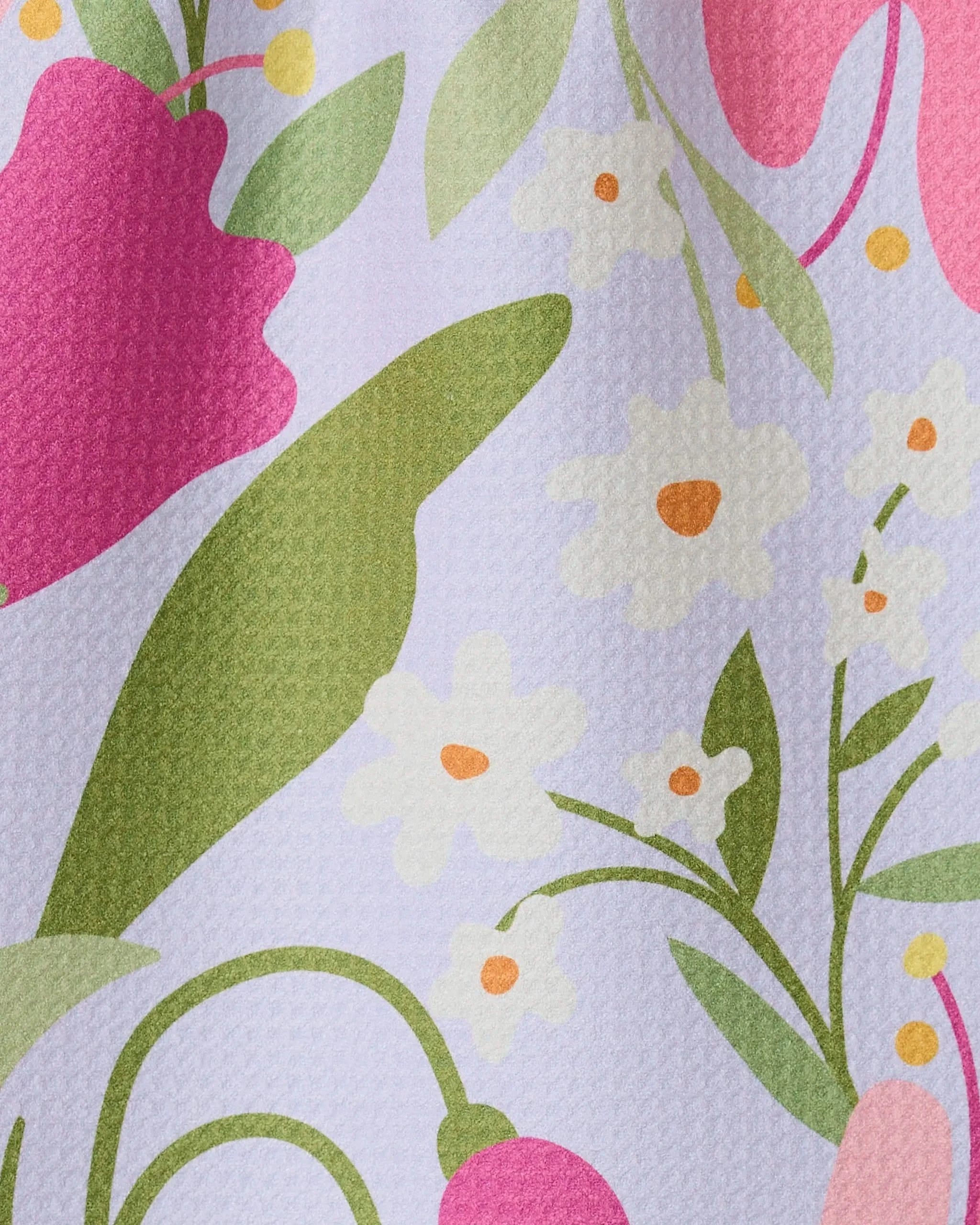 A close-up of the GEOMETRY Thoughtful bar towel, made from recycled materials, featuring a colorful floral print with large green leaves, pink flowers, and small white-and-yellow blossoms on a light background.