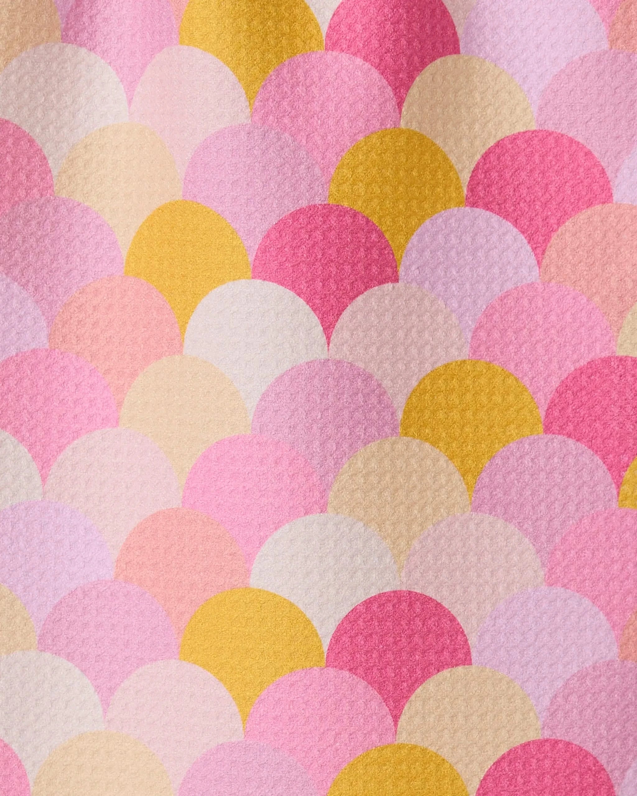The GEOMETRY Inherit towel features a colorful pattern of overlapping scalloped shapes in pink, yellow, cream, and peach with a textured, ultra-absorbent surface—resembling fish scales or a mermaid tail.