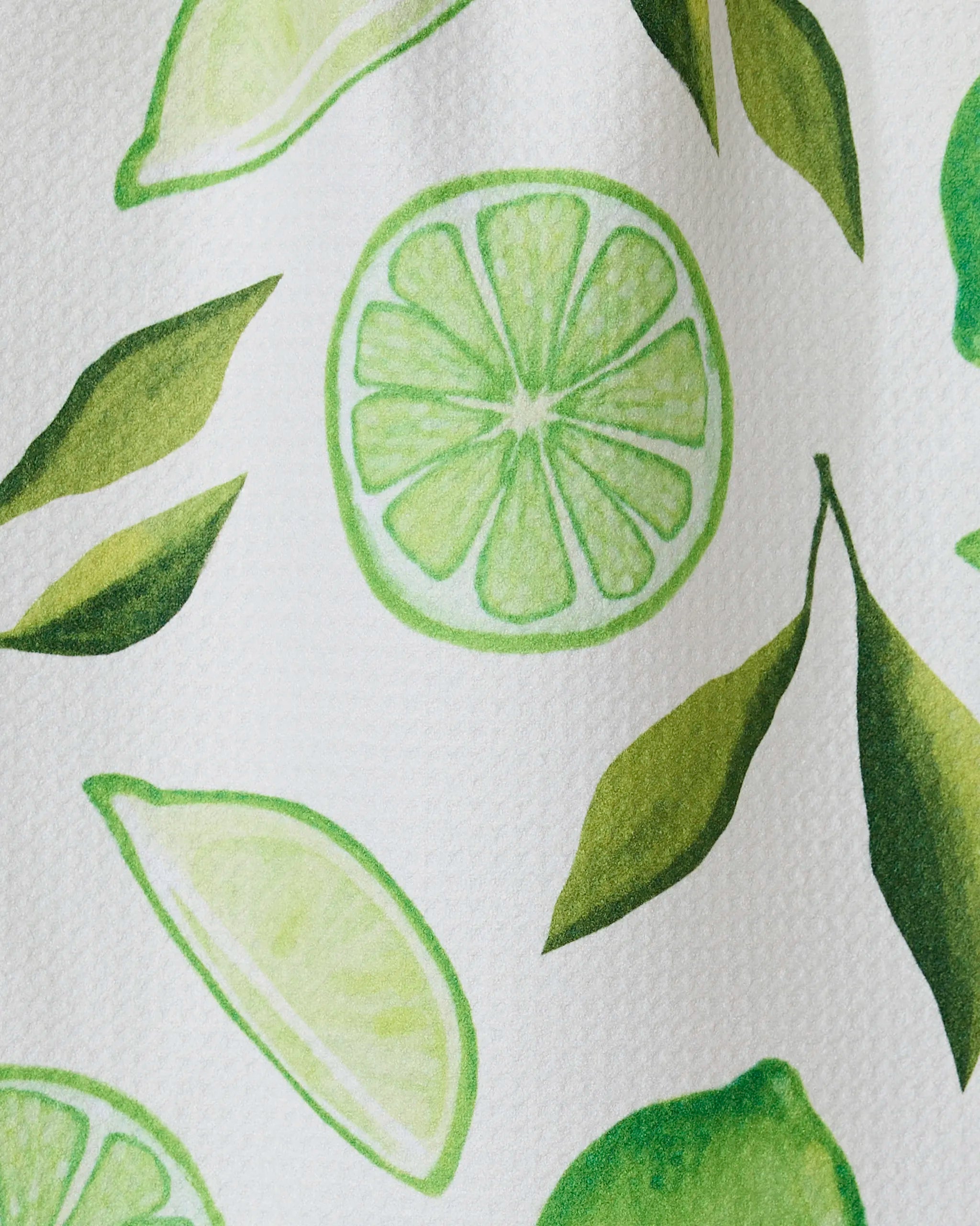 The GEOMETRY Lima bar towel features a bright, fresh pattern of green lime slices, halves, and leaves on soft Geoweave fabric made from recycled materials. The hand-drawn design appears on a white background.