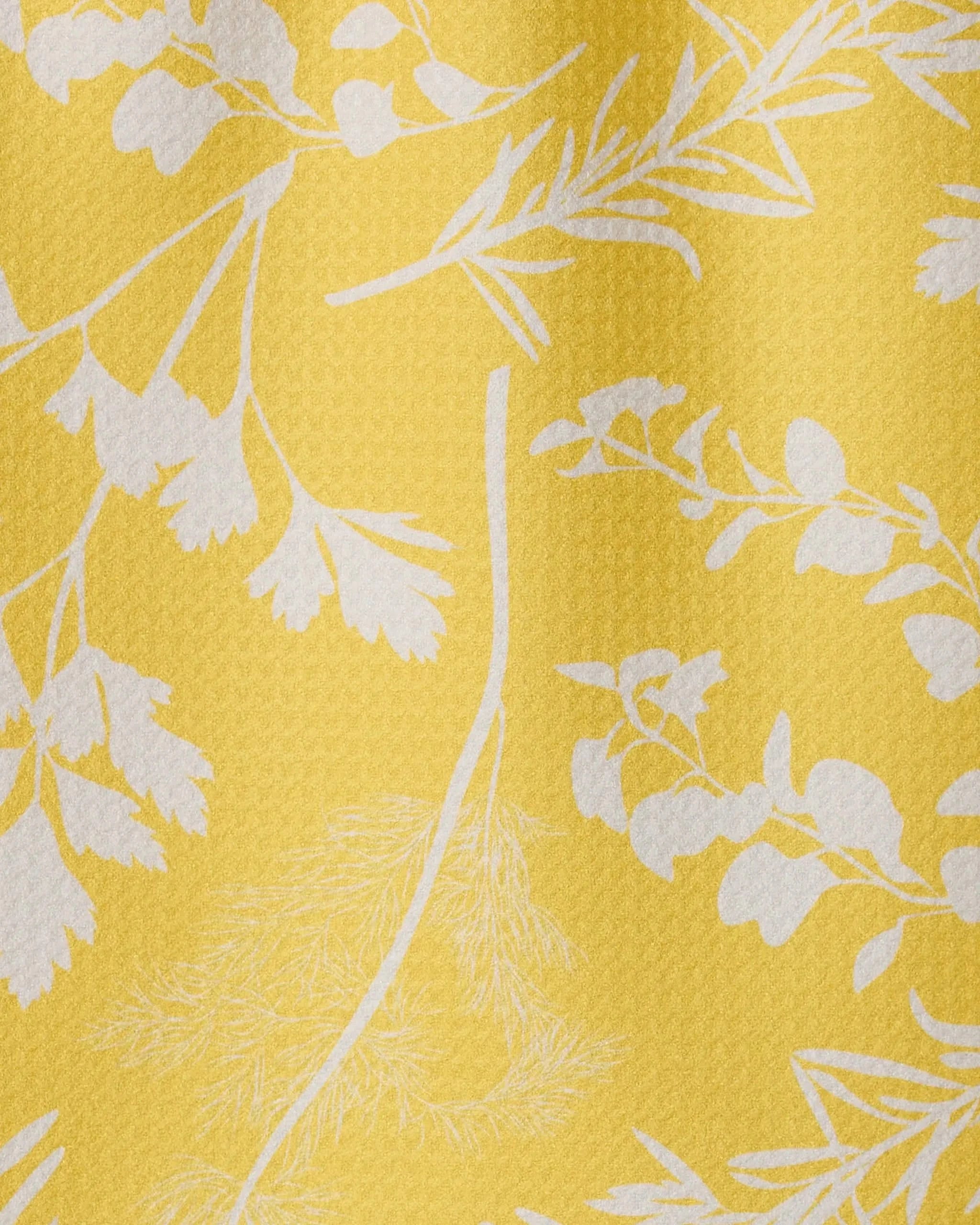 The Garden of Gold towel by GEOMETRY features yellow textured fabric with white leaf and flower silhouettes, made from recycled materials for style, sustainability, and ultra-absorbency.