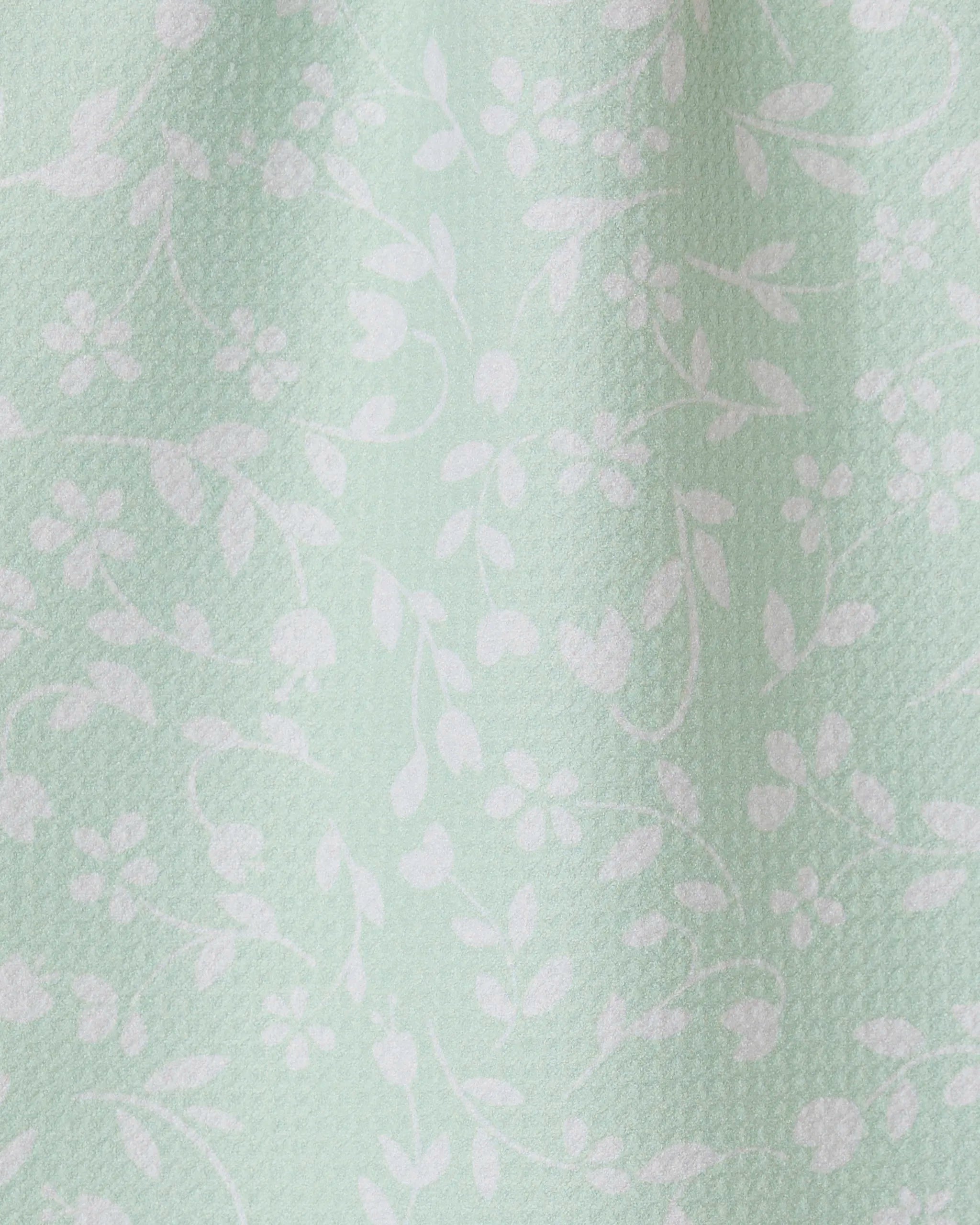 The Dandy towel by GEOMETRY features light mint green fabric with a subtle texture and delicate white floral vine pattern. Ultra-absorbent, it drapes softly for an elegant, functional touch in your space.