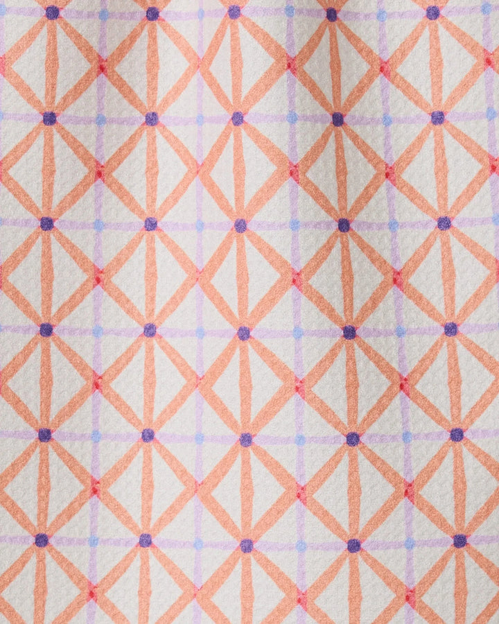 Anew by GEOMETRY is a patterned bar towel with intersecting orange and pink lines forming diamond shapes, accented by purple dots on a light background. Made from recycled materials for an eco-friendly touch.
