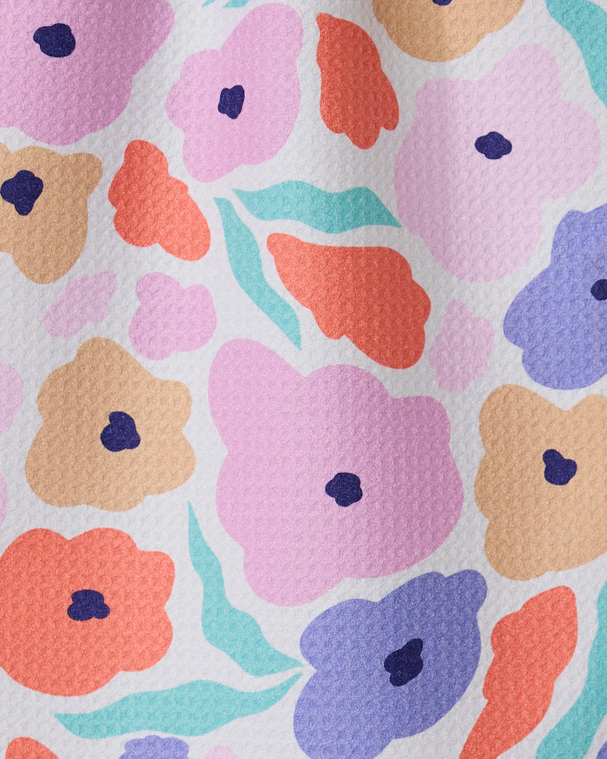 A close-up of GEOMETRYs Blossoming Love shows textured recycled fabric with an abstract floral design in pink, orange, purple, tan, and mint green on a white background.