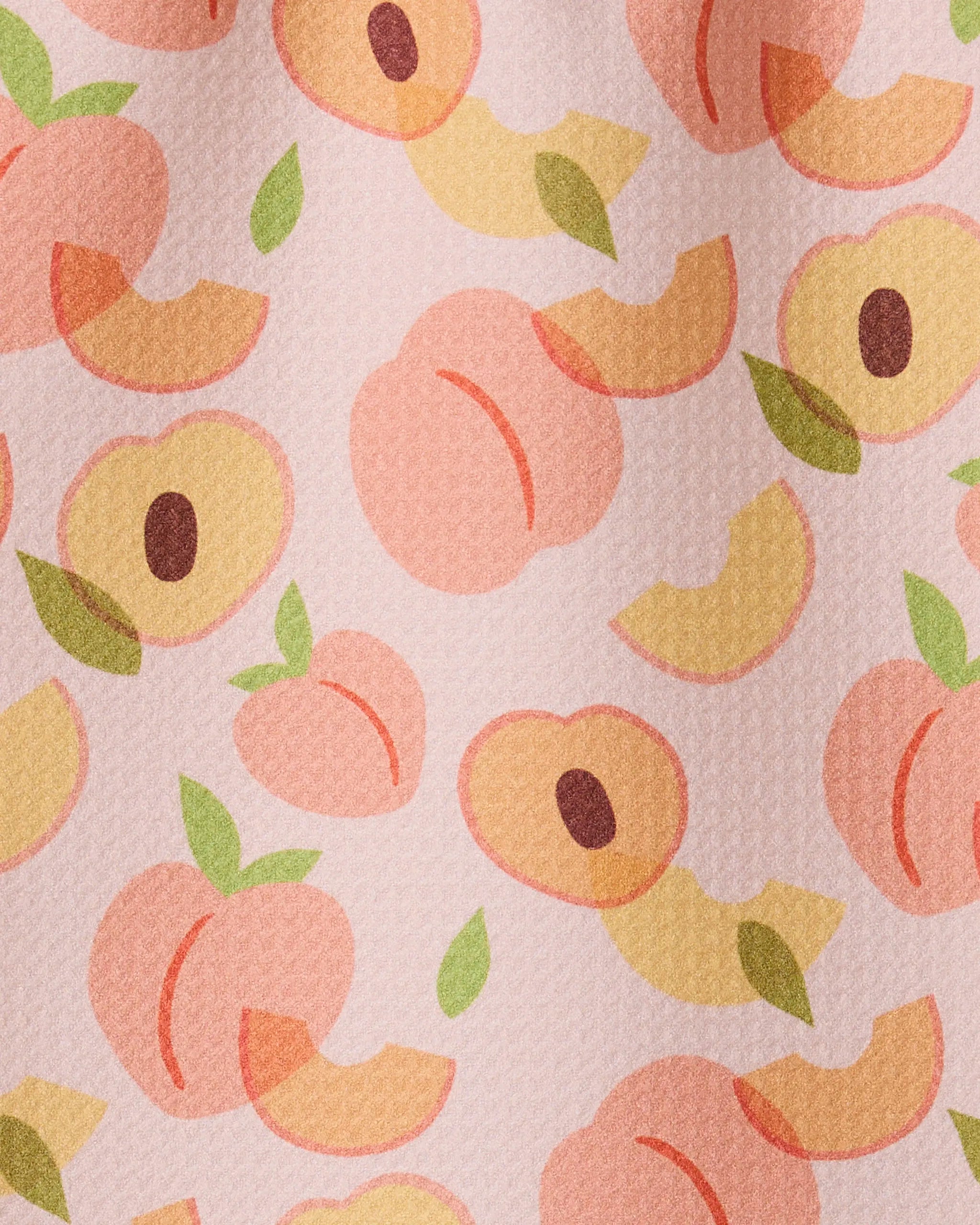 The GEOMETRY Peaches towel features a seamless design of whole and sliced peaches with green leaves on a textured light pink background, crafted from ultra-absorbent recycled materials.