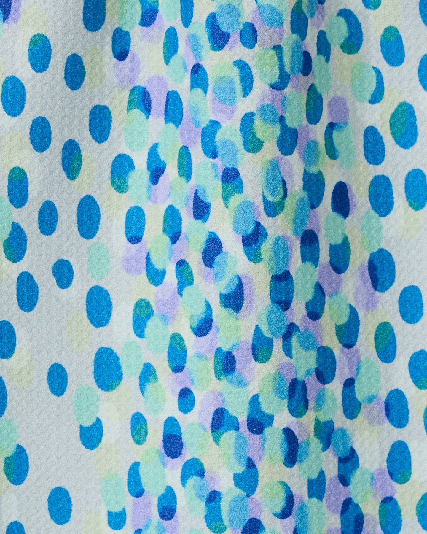 A close-up of Spotty Summer by GEOMETRY shows a vibrant, abstract bar towel made from recycled materials, featuring blue, green, and purple dots scattered across a white background.
