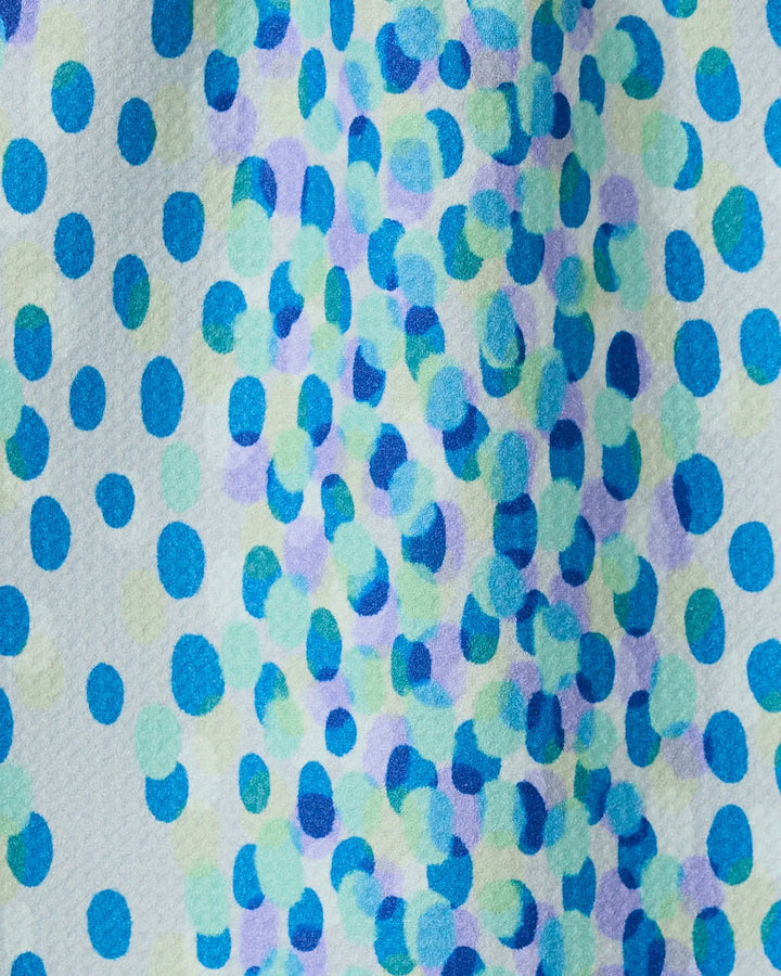 A close-up of Spotty Summer by GEOMETRY shows a vibrant, abstract bar towel made from recycled materials, featuring blue, green, and purple dots scattered across a white background.