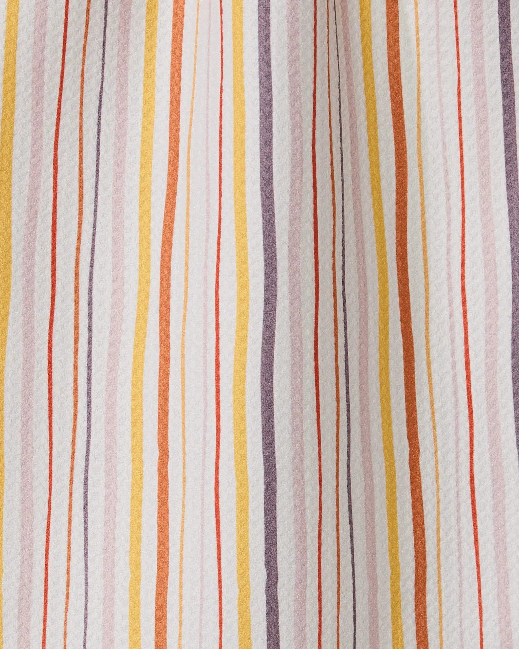 A close-up of Stripe Season by GEOMETRY: fabric crafted from recycled materials, featuring vertical wavy stripes in orange, yellow, purple, and red on a white background with varied thickness and spacing.