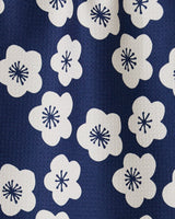 A close-up of GEOMETRYs Every Sunday kitchen towel showcases blue fabric with white floral patterns and dark blue centers. Its slightly pebbled texture adds style, while ultra-absorbency makes it perfect for daily use.