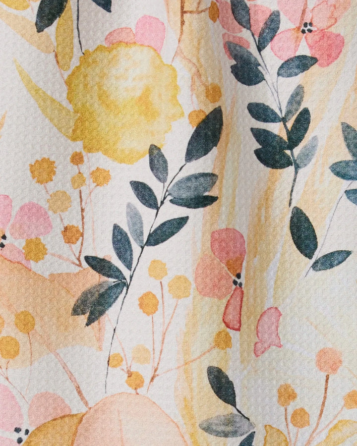 Sleepy Fields by GEOMETRY features pastel flowers and green leaves in soft yellow, pink, and peach on textured paper—an eco-friendly design inspired by recycled materials and the feel of an ultra-absorbent towel.