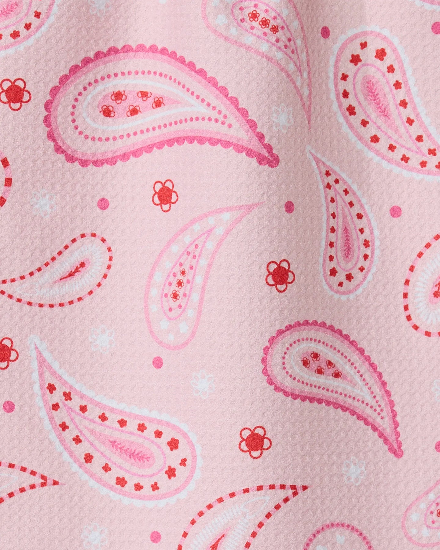 Close-up of the GEOMETRY Sweet Paisley ultra-absorbent towel with pink textured fabric, accented by paisley patterns and small floral designs in pink, red, and white.