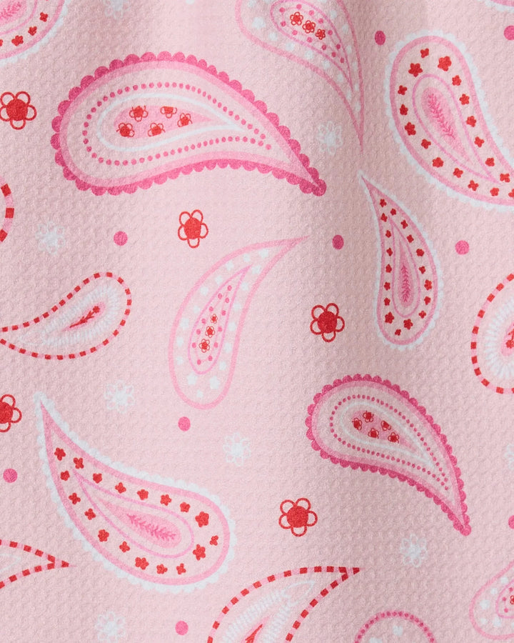 Close-up of the GEOMETRY Sweet Paisley ultra-absorbent towel with pink textured fabric, accented by paisley patterns and small floral designs in pink, red, and white.