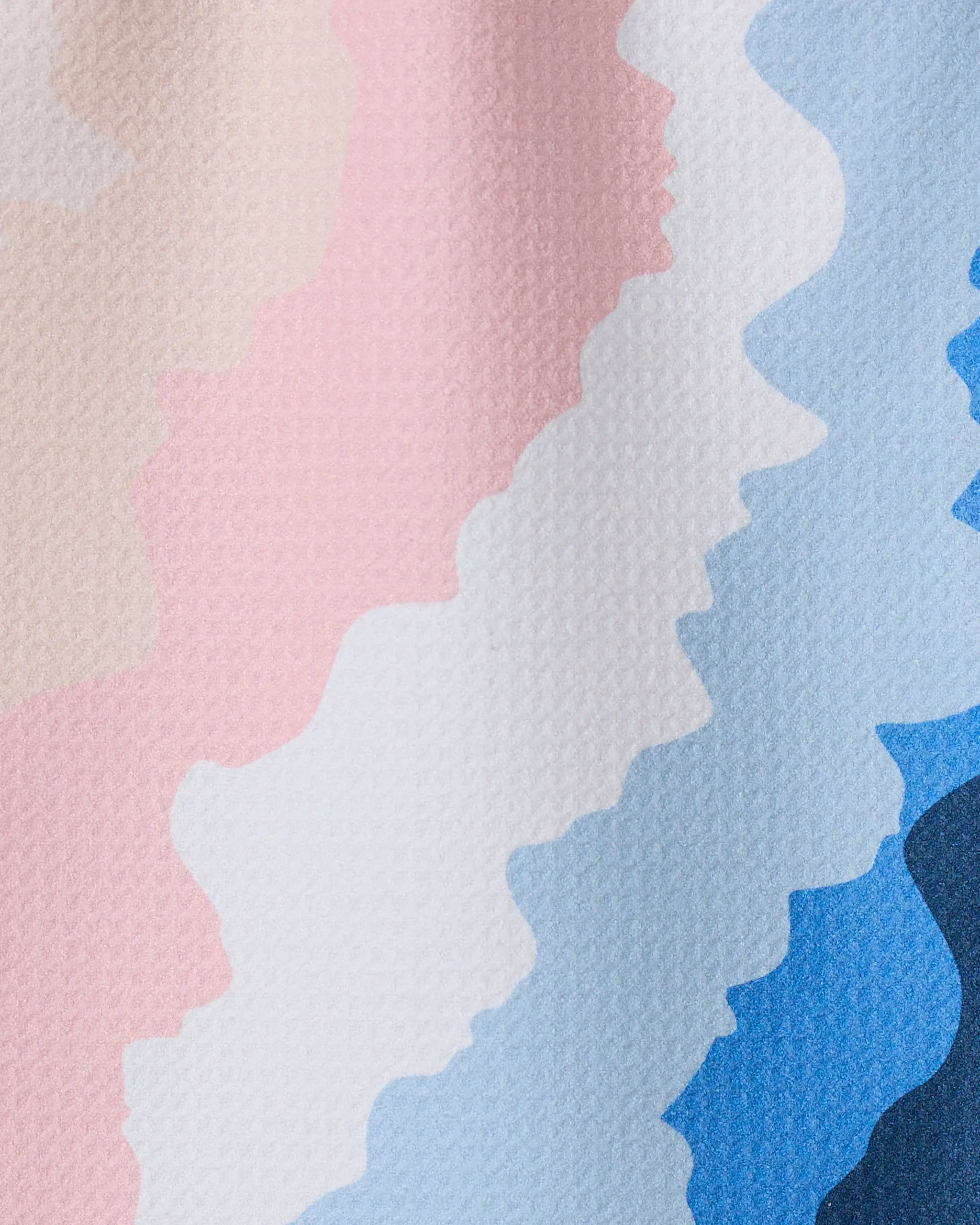 GEOMETRY’s “Shore” features wavy, horizontal stripes in pastel pink, cream, white, light blue, and blue on a lightly textured surface, with colors blending softly in a zigzag pattern reminiscent of recycled kitchen towels.