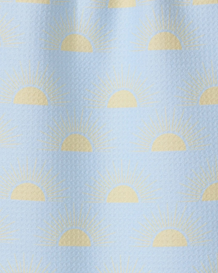 Soft Summer Sun by GEOMETRY is a light blue textured fabric made from recycled materials, featuring yellow half-sun sunrise motifs and radiating rays in an evenly spaced, repeating pattern.
