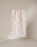 The GEOMETRY Lobster Love towel, ultra-absorbent and white with a pattern of yellow and pink cartoon cheetahs, hangs on a clothesline against a plain, light background.