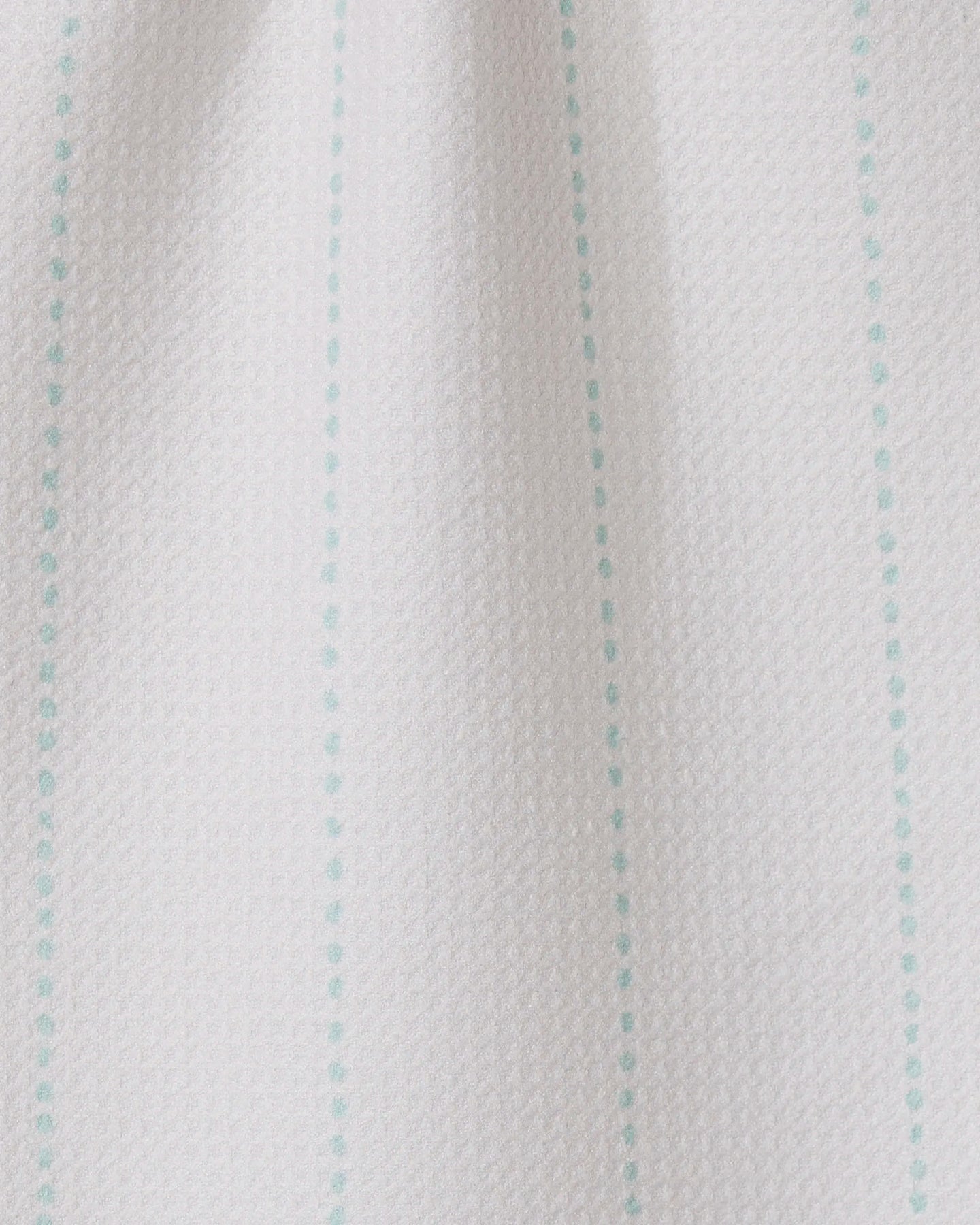 Close-up of GEOMETRY’s Dotted Dunes: white textured fabric featuring evenly spaced turquoise vertical dotted lines—a minimal, simple design perfect for ultra-absorbent towels made from recycled materials.