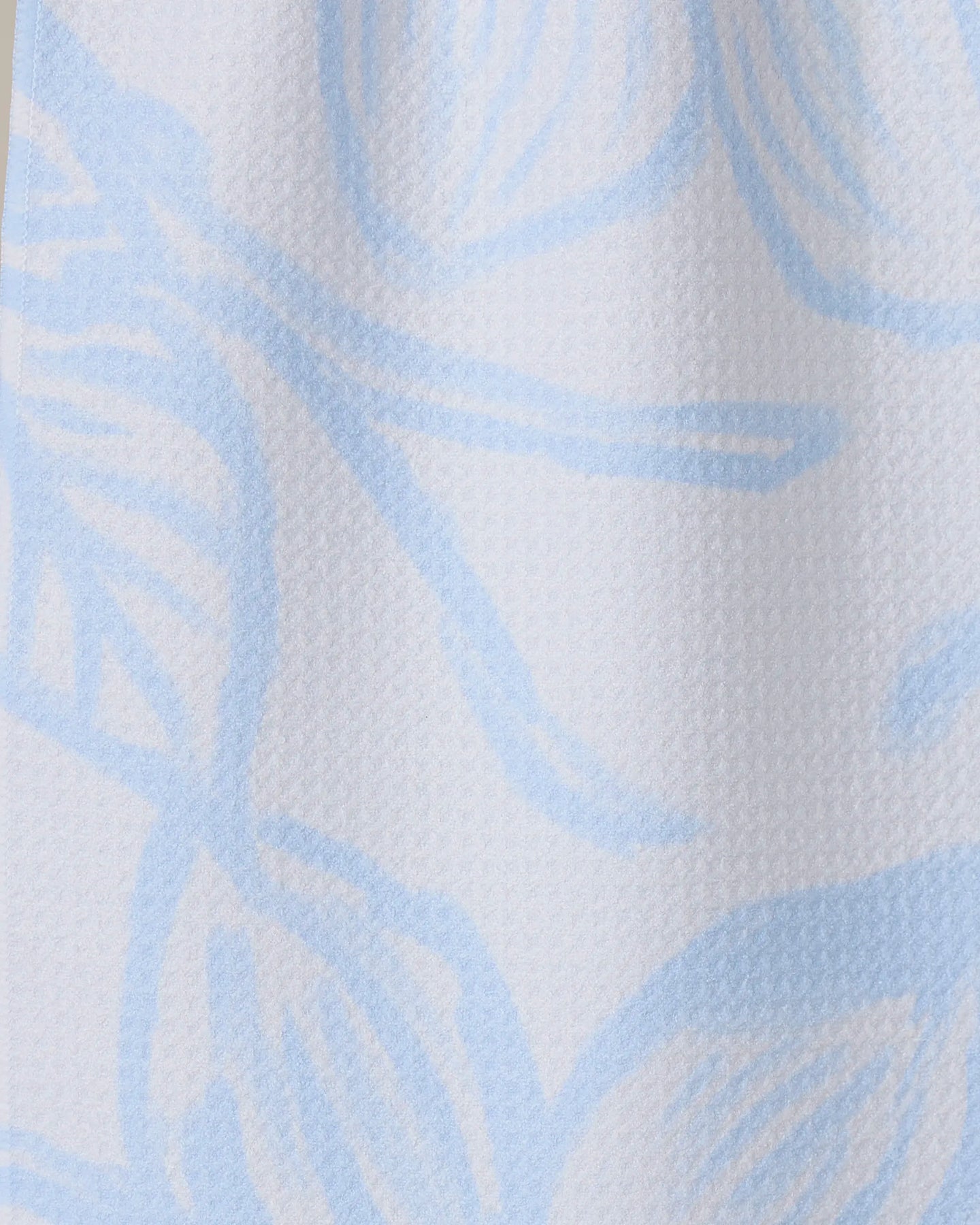 Close-up of GEOMETRY’s Something Blue, featuring textured white Geoweave fabric with a soft surface and a light blue abstract floral pattern of large, flowing lines and petal-like shapes.